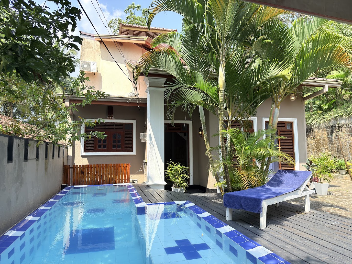 Blue-tiled swimming pool beside the villa and tropical palms