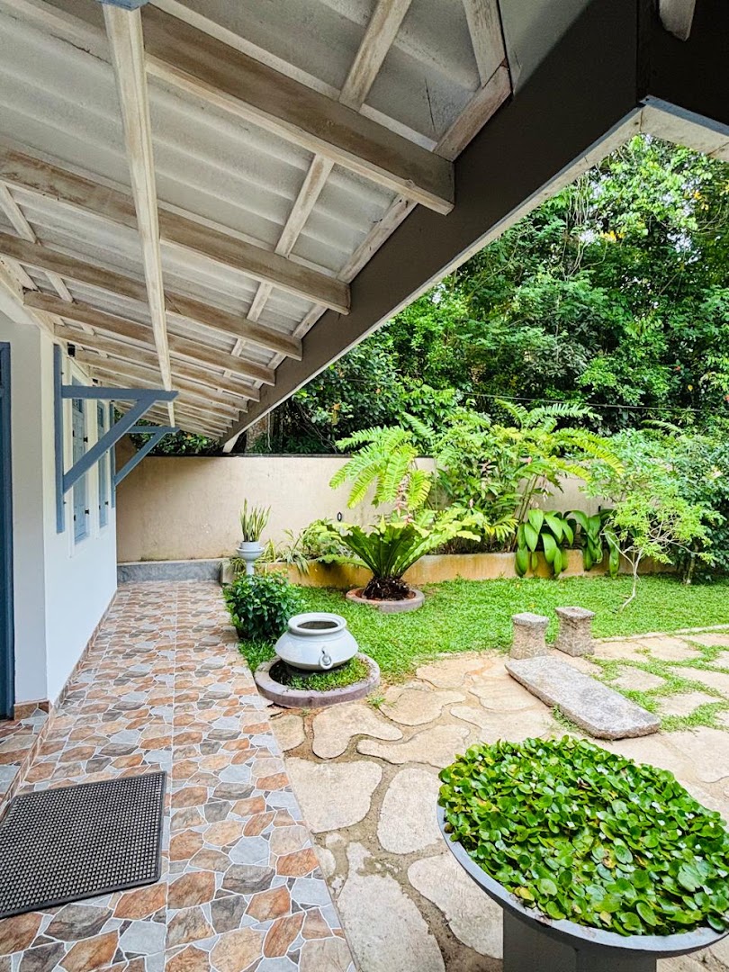 Covered veranda beside a lush tropical garden and stone path