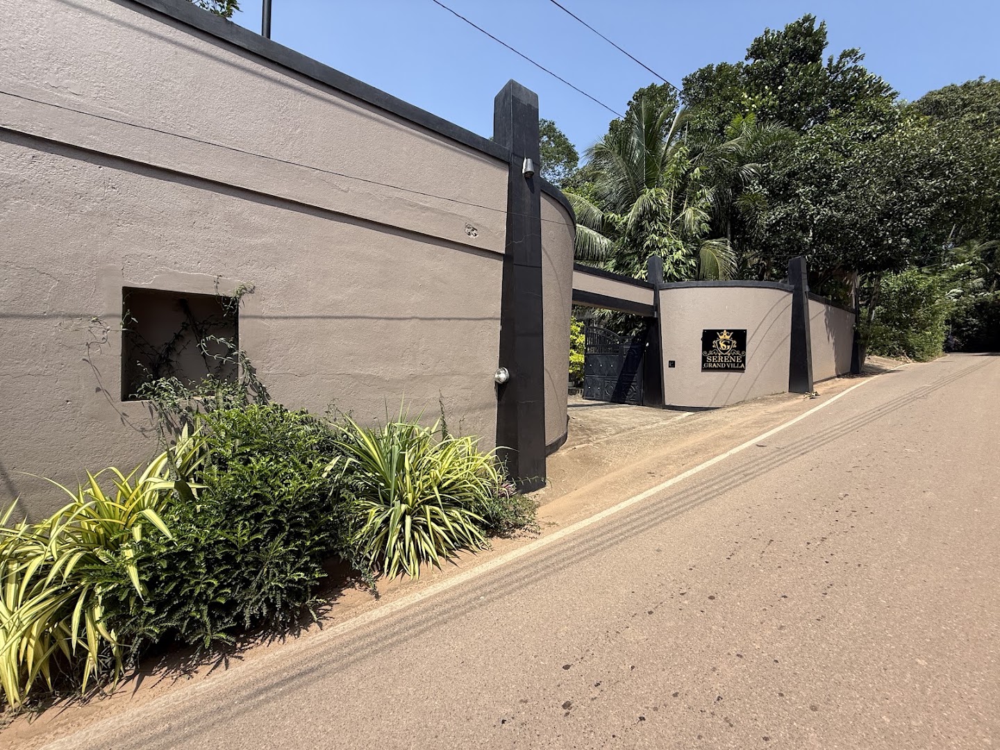 Entrance wall and Serene Grand Villa sign beside the road